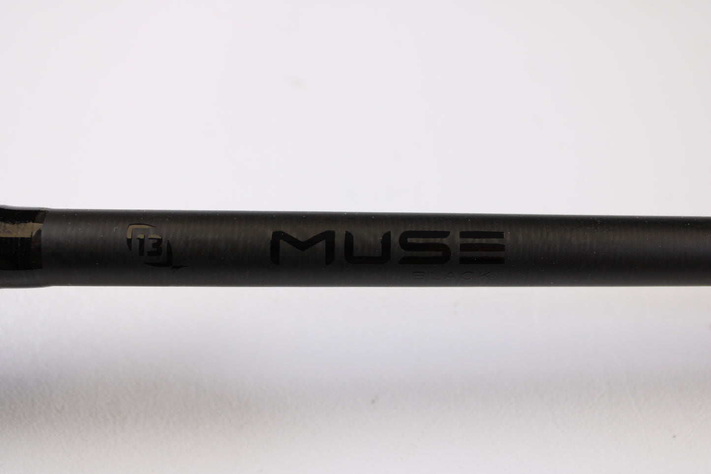 A close-up of a black 13 Fishing Muse 7'6" Medium Heavy used casting rod in excellent condition, with "MUSE" and "ENVE" visible and a small "13" logo on the left. Ideal for those seeking used gear or interested in our rod and reel trade-in program. Plain white background.