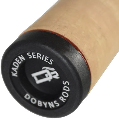 Close-up of a Dobyns Kaden Casting Rod 7'1" Heavy handle, adorned with a full cork grip. The black end cap reads "Kaden Series Dobyns Rods," featuring a stylized fish logo. The handle, made with high modulus blanks, is shown at an angle.