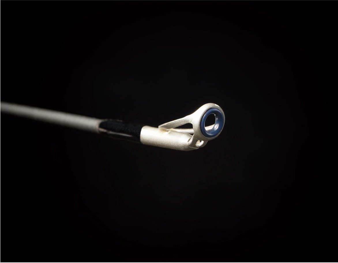 A close-up of a metallic fishing rod guide on a Falcon Cara Casting Rod Deep Runner 7'3" Medium Heavy (CC-5-173DR) against a black background, highlighting the circular eyelet and carbon fiber shaft.