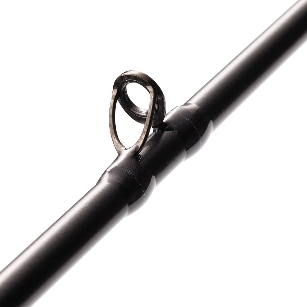 Close-up of the St. Croix Legend Xtreme 7’4” Heavy Casting Rod by americanlegacyfishing, highlighting a polished metal guide ring. The cylindrical guide stands out against the smooth, dark rod surface featuring Advanced Reinforcing Technology, all set against a white blurred background.