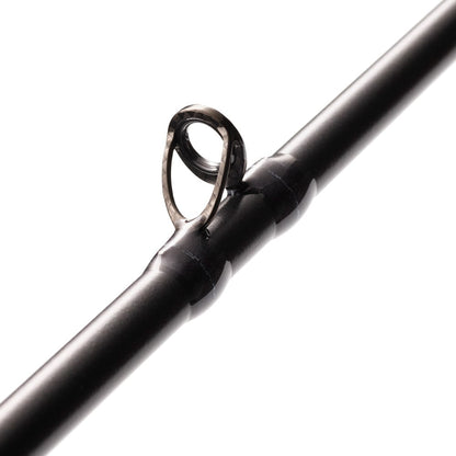 Close-up of the St. Croix Legend Xtreme 7’4” Heavy Casting Rod by americanlegacyfishing, highlighting a polished metal guide ring. The cylindrical guide stands out against the smooth, dark rod surface featuring Advanced Reinforcing Technology, all set against a white blurred background.