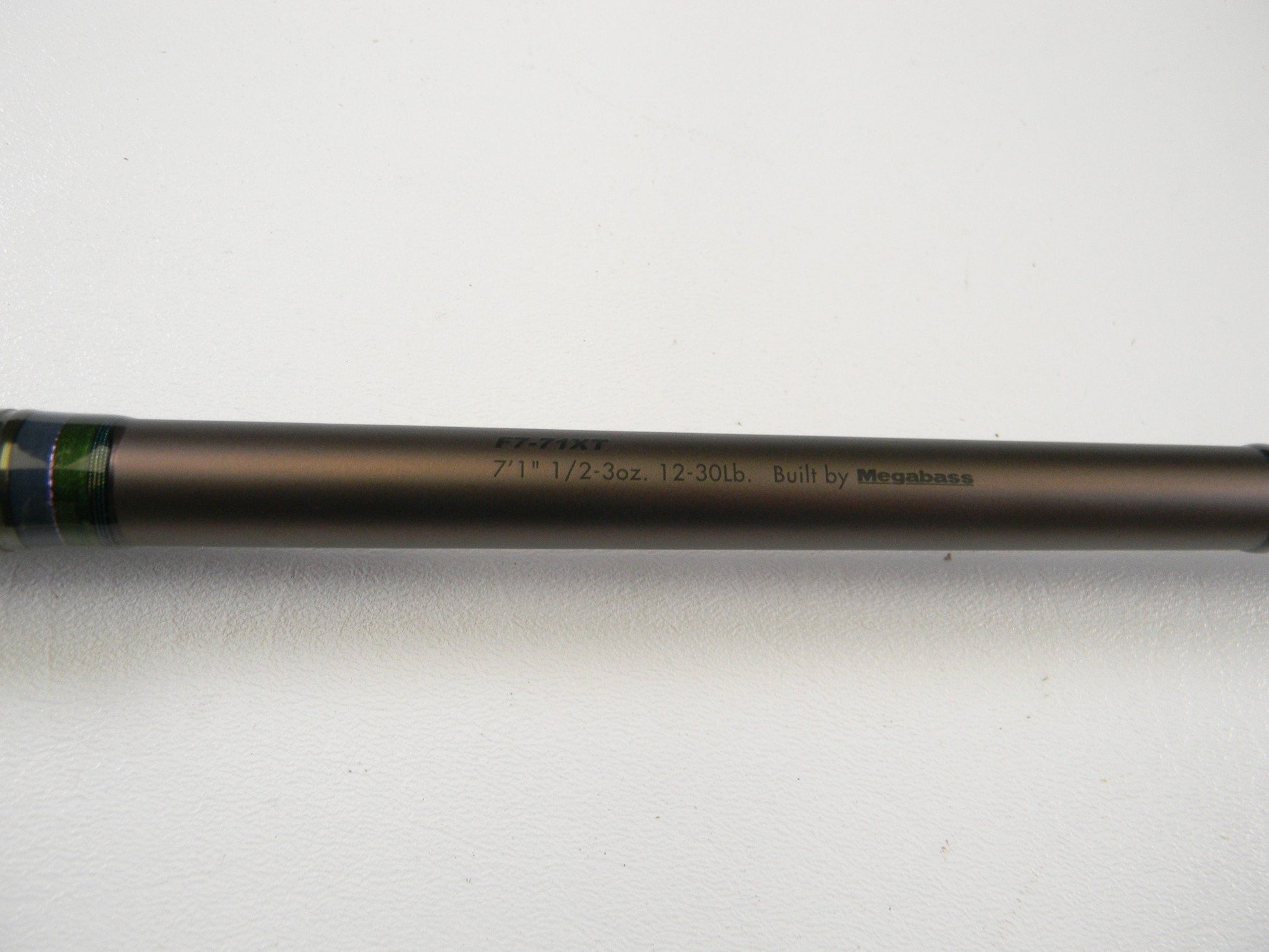 A close-up of the Megabass Orochi X10 F7-71XT Swamp Survivor 7'1" Heavy Casting Rod in excellent used condition, featuring printed specs on a metallic brown shaft—ideal for upgrading your gear or rod and reel trade-ins.