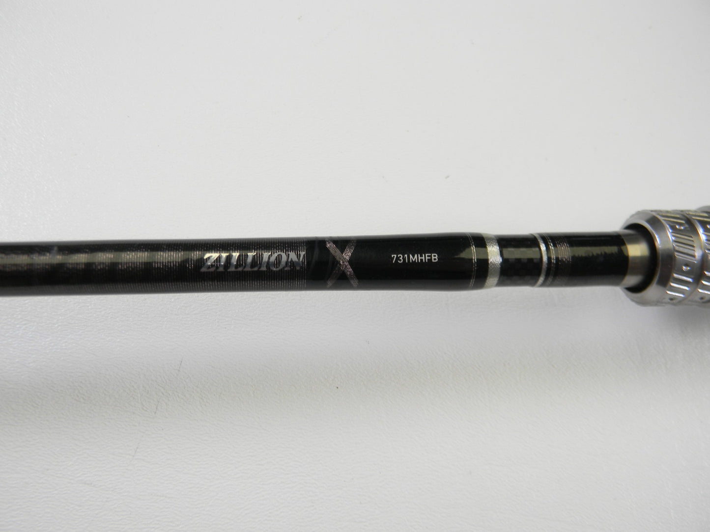 A close-up of the Daiwa Zillion ZIL731MHFB 7'3" Medium Heavy Used Casting Rod in excellent condition displays "ZILLION X 731MHFB" on its black and silver handle, ideal for the Rod and Reel Trade-In Program, against a white background.