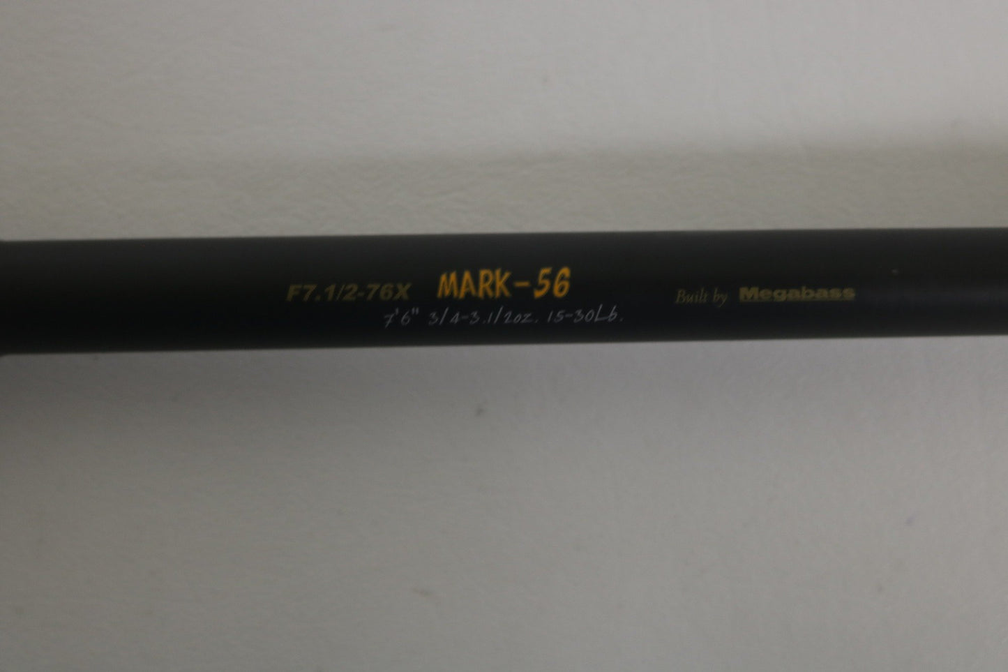 A close-up of the Megabass Destroyer P5 F7.1/2-76X Used Casting Rod, showing yellow and white model text on its black finish, with a plain light background. Brand: Megabass. Condition: Excellent.