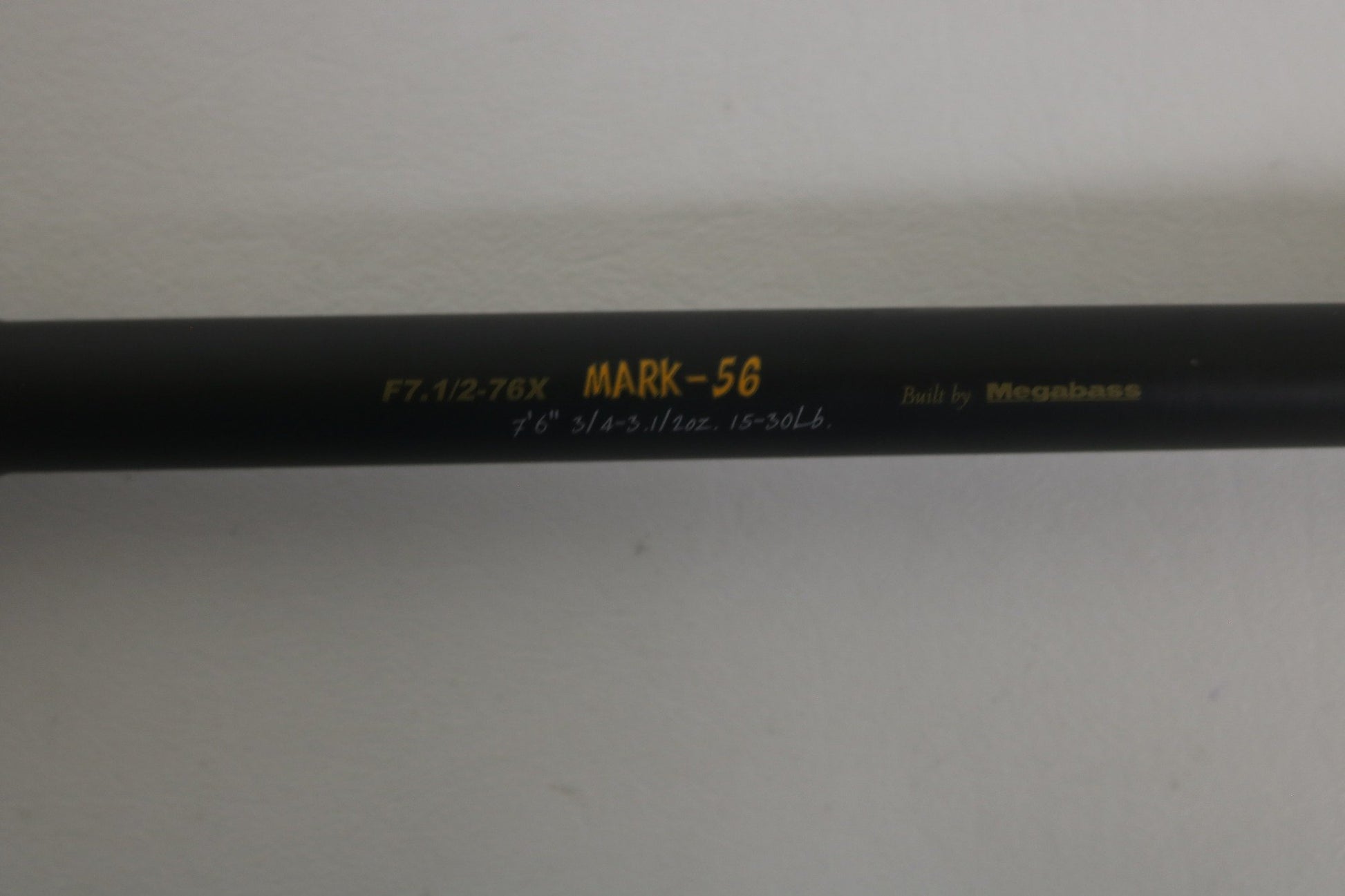 A close-up of the Megabass Destroyer P5 F7.1/2-76X Used Casting Rod, showing yellow and white model text on its black finish, with a plain light background. Brand: Megabass. Condition: Excellent.