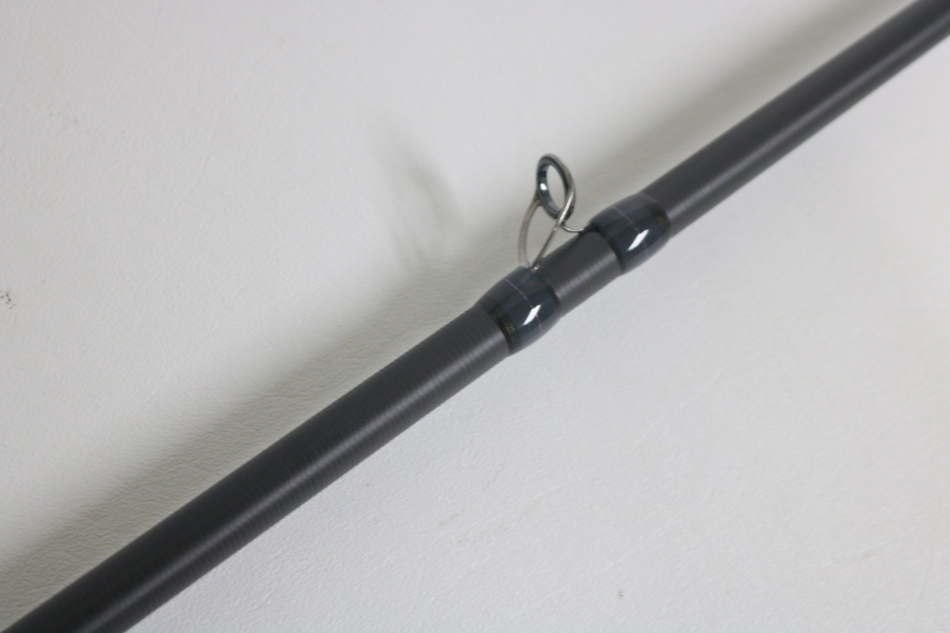 Close-up of a Megabass Destroyer P5 F7.1/2-76X Used Casting Rod in excellent condition, highlighting one of its black line guides against a plain white background.
