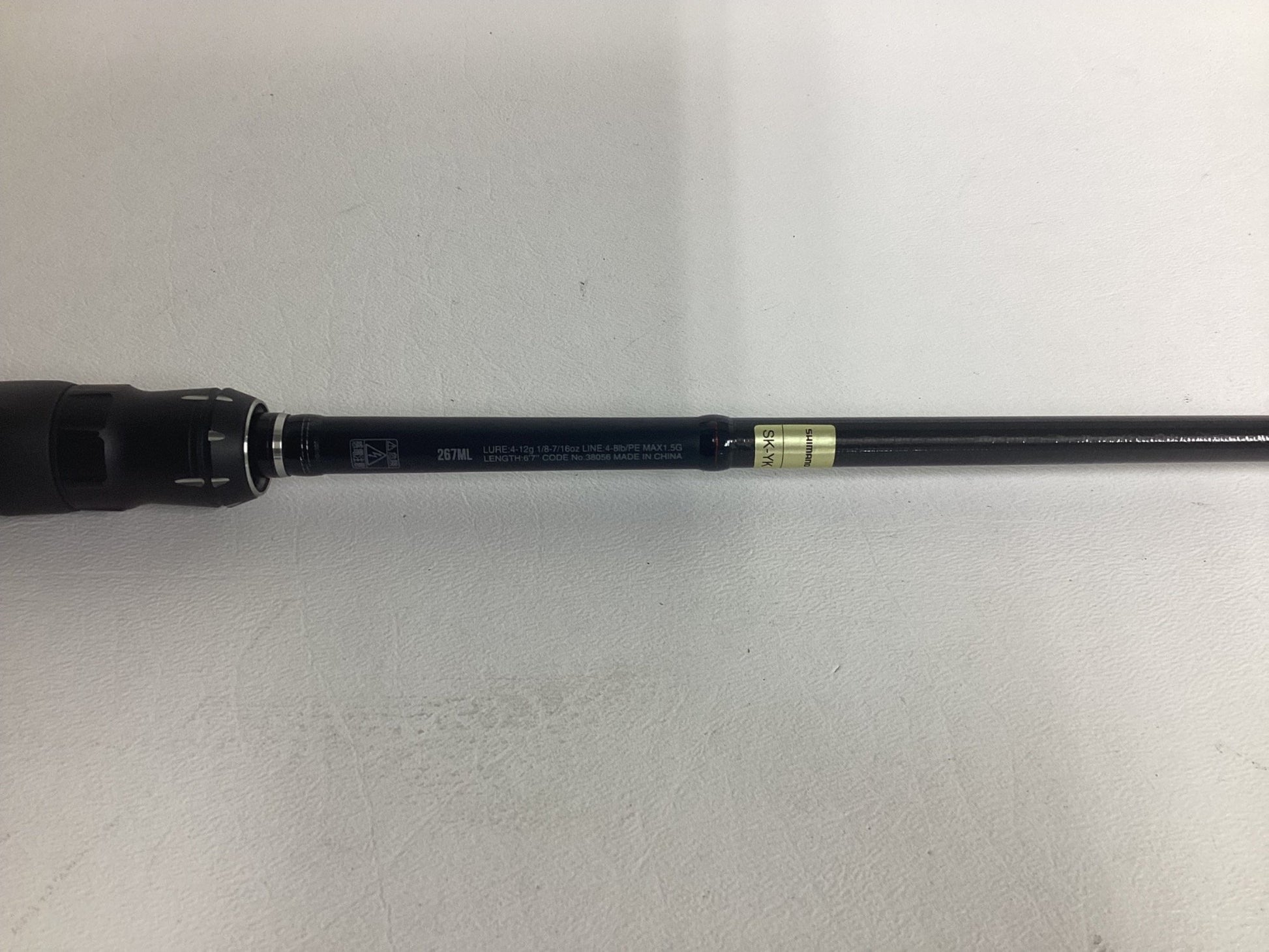 Close-up of a Shimano Poison Adrena PAD267MLA 6'7" Medium Light used spinning rod in excellent condition, showing printed specs on the black handle—great for those seeking quality pre-owned fishing gear by Shimano.