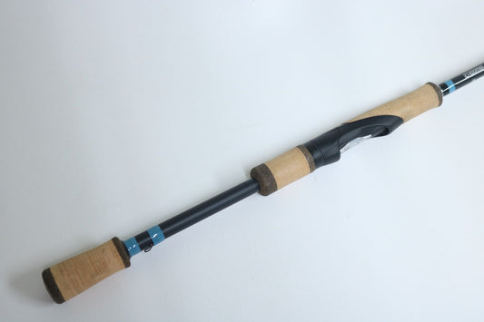 A G. Loomis NRX+ 802S JWR Used Spinning Rod in mint condition with a black body, blue accents, and cork handles is shown on a white background—ideal for your next rod and reel trade-in or to earn store credit.