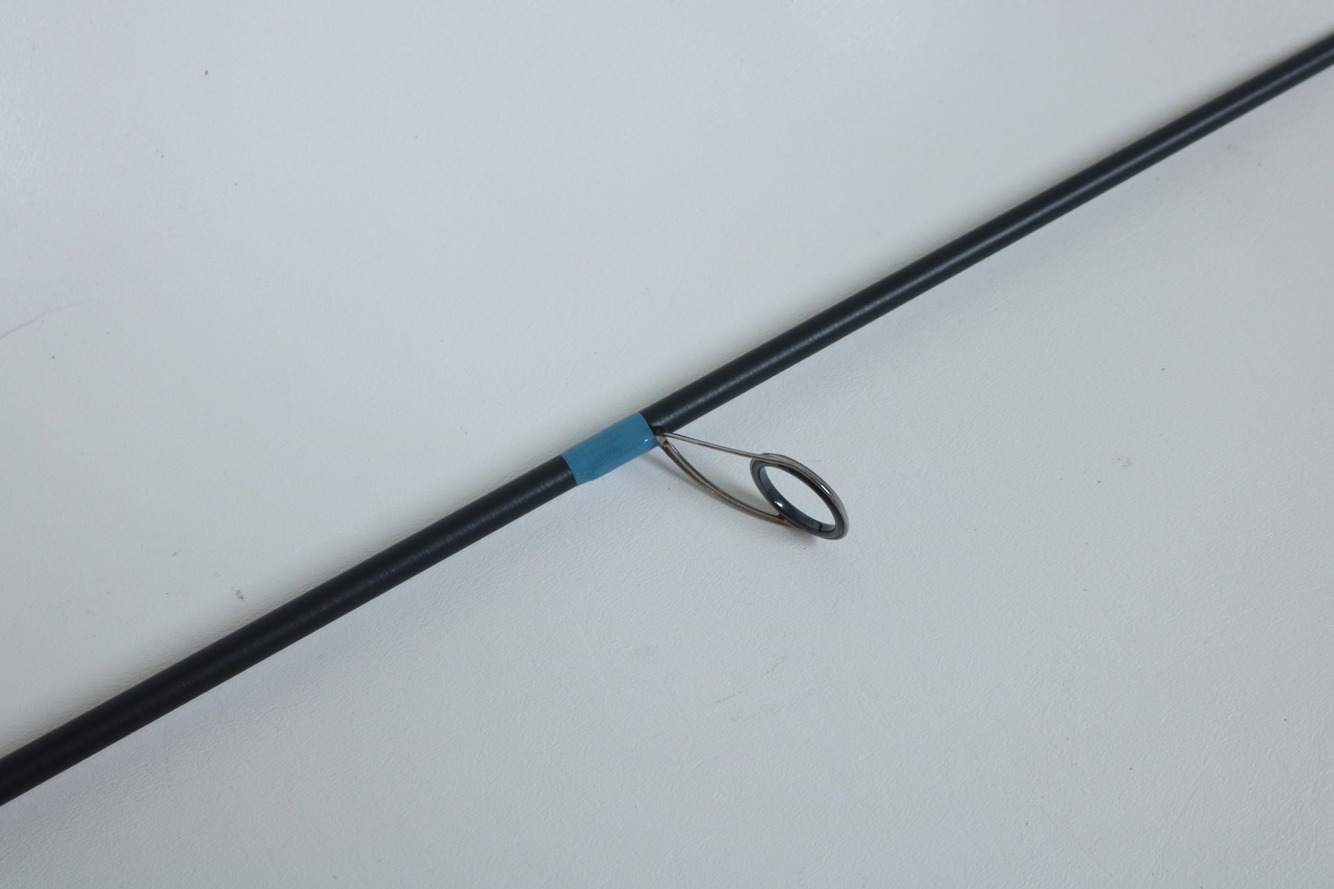 A close-up of a G. Loomis NRX+ 802S JWR Used Spinning Rod in mint condition, featuring a metal guide ring and blue wrap—ideal for anglers seeking quality used gear or exploring our rod and reel trade-in program.