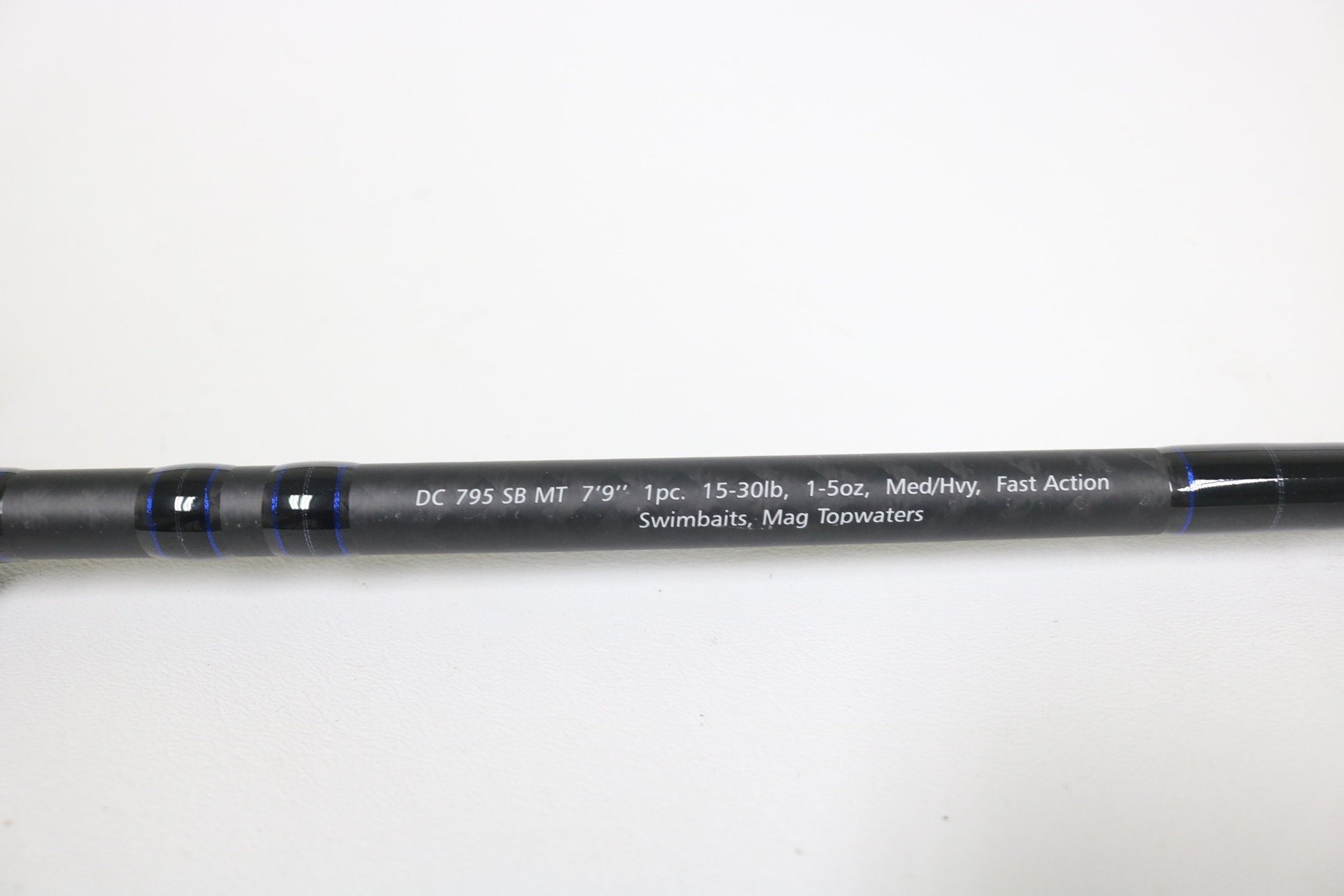 A close-up of the Dobyns Champion XP DC 795SB MT 7'9" Medium Heavy Used Casting Rod in excellent condition, shown on a black background with blue accents—ideal for our rod and reel trade-in program.