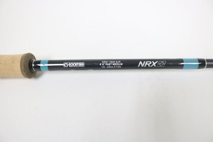A close-up shows a G. Loomis NRX+ 782s SJR 6'6" Medium Used Spinning Rod in excellent condition, ideal for Rod and Reel Trade-In or store credit, featuring a black and blue shaft with cork handle.