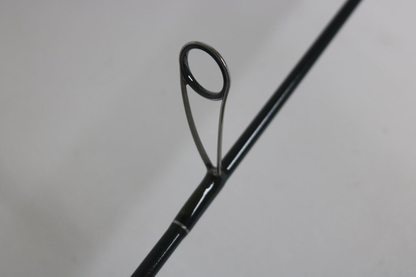 Close-up of a St. Croix Legend Elite ES60MLF 6'0" Medium Light used spinning rod guide—metal ring and support visible, ideal for those interested in upgrading with our Rod and Reel Trade-In Program. Mint condition from St. Croix.