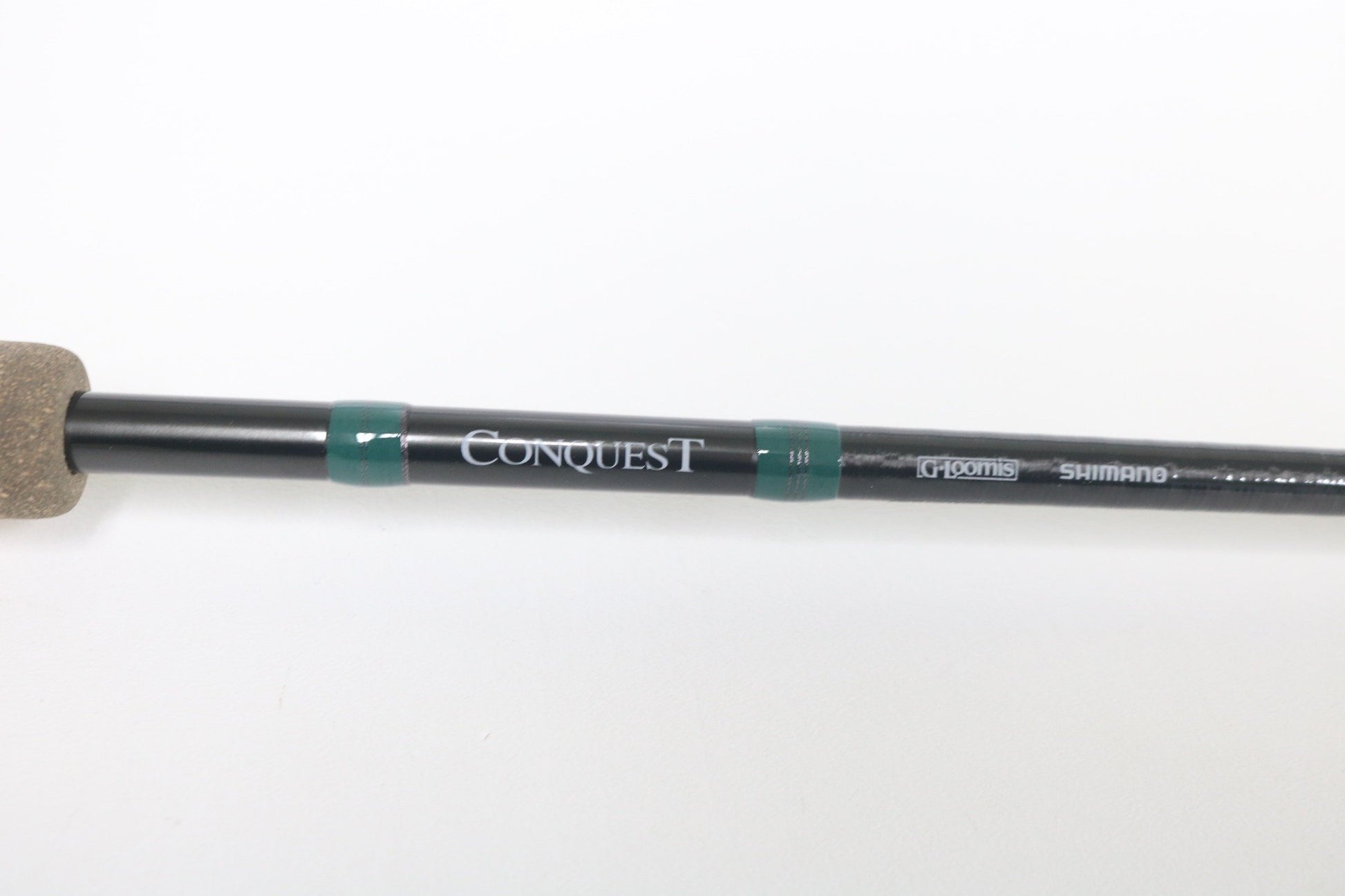 Close-up of a used G. Loomis Conquest CNQ 843C MBR Casting Rod in mint condition, displaying “Conquest” and G. Loomis branding on a white background. Trade in your gear for store credit with our Rod and Reel Trade-In Program.
