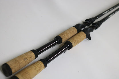 Two Temple Fork TFO Tactical Bass TAC SB 726-1 and TAC SC 746-1 casting rods in good used condition with cork handles and black reel seats lie diagonally—ideal for upgrading or earning store credit through our trade-in program.