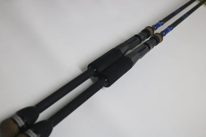 Two Mustad BLF Instinct 7'4" Medium Heavy Casting Rods, used and in very good condition, lie parallel on a white surface—ideal for anglers seeking quality gear through the Nation's Best Rod and Reel Trade-In Program.