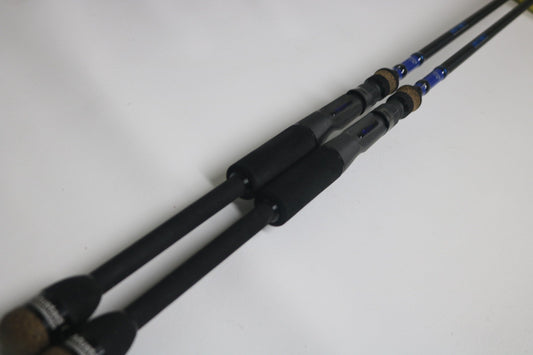 Two Mustad BLF Instinct 7'4" Medium Heavy Casting Rods, used and in very good condition, lie parallel on a white surface—ideal for anglers seeking quality gear through the Nation's Best Rod and Reel Trade-In Program.