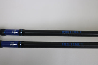 Two Mustad BLF Instinct 7'4" Medium Heavy Casting Rods in very good used condition lie parallel on a white surface. Trade in your used gear through our Nation's Best Rod and Reel Trade-In Program for store credit.