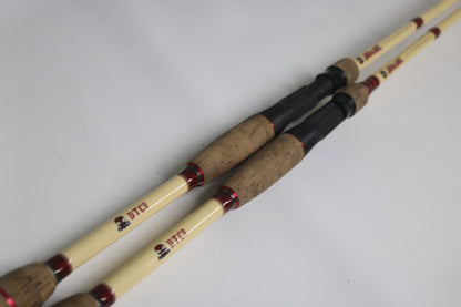 Two Doomsday The47 T47C-673F Casting Rods (used, fair condition) with light shafts, cork handles, and red accents are side by side on a white surface. Trade in your used gear for store credit at the Rod and Reel Trade-In event!.