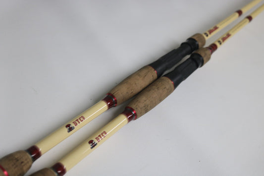Two Doomsday The47 T47C-673F Casting Rods (used, fair condition) with light shafts, cork handles, and red accents are side by side on a white surface. Trade in your used gear for store credit at the Rod and Reel Trade-In event!.