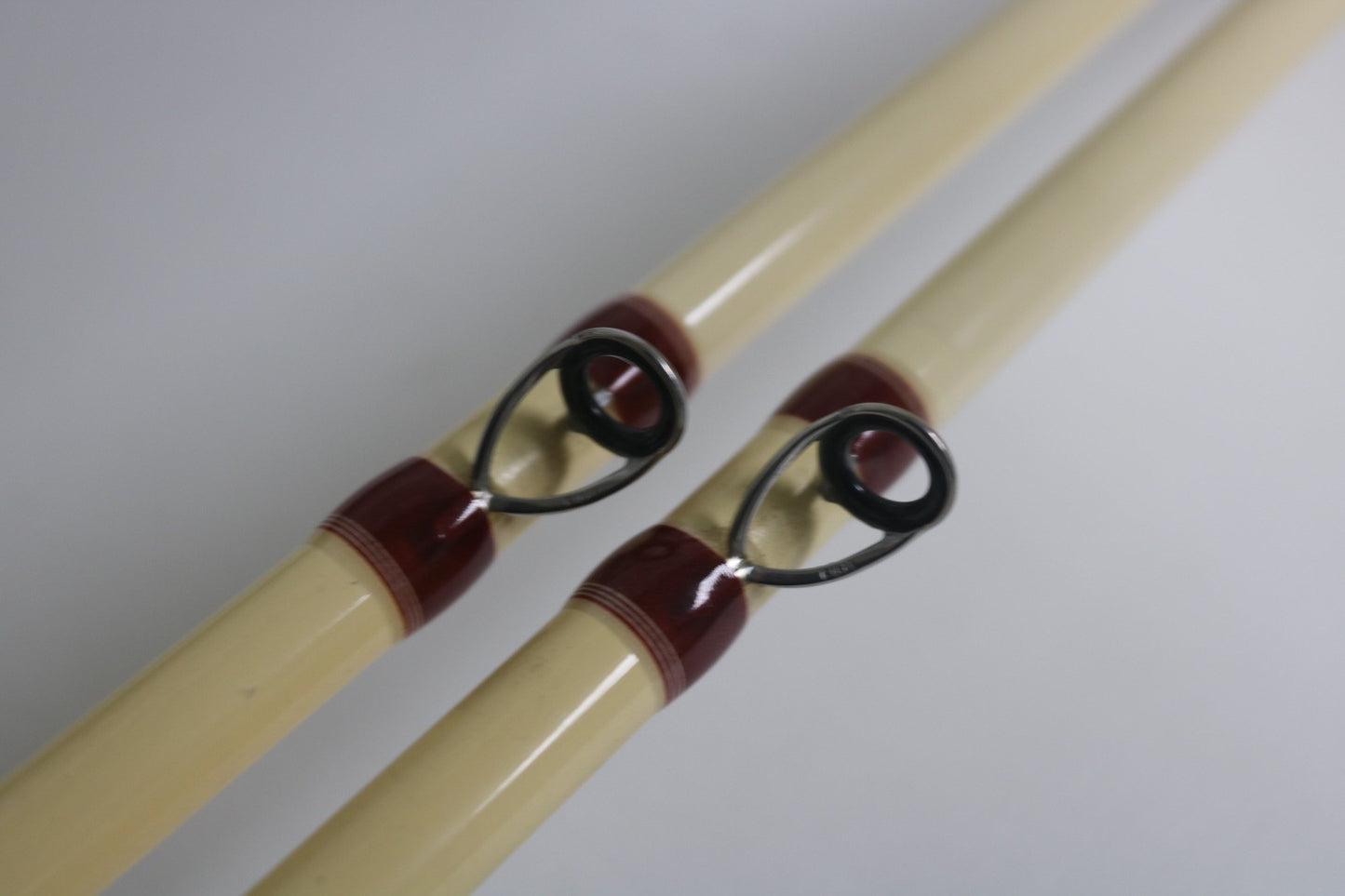 Close-up of two Doomsday The47 T47C-673F Casting Rods in fair used condition, cream-colored with black guides and maroon wrappings, shown parallel on a white background—ideal for trade-in or expanding your used gear collection.