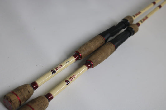 Two Doomsday The47 T47C-573F Casting Rods in fair used condition, with cream shafts, red accents, and cork handles, are displayed side by side—ideal for our Rod and Reel Trade-In Program for used gear.