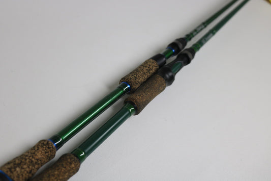 Two SixGill Aura/Fenrir casting rods (ANURC705H & FENRC702MH), used in very good condition, lie side by side on a white surface—ideal for Rod and Reel Trade-In or increasing your store credit with quality gear.