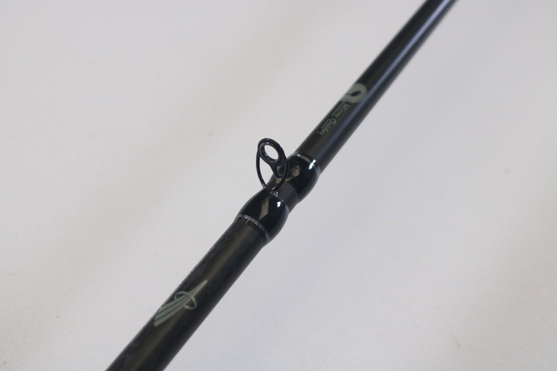 A close-up of a Waft Iron Feather 7'0" Medium Heavy used casting rod, highlighting a line guide against a white background—ideal for evaluating gear condition before a Rod and Reel Trade-In.