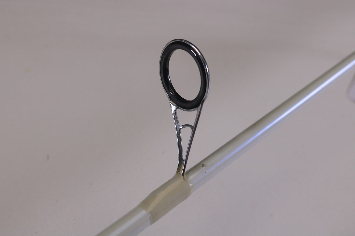Close-up of the guide ring on a Duckett White Ice TR-DFWI68MHS 6'8" Medium Heavy Used Spinning Rod in good condition. Perfect for used gear enthusiasts or those considering our Rod and Reel Trade-In for store credit.