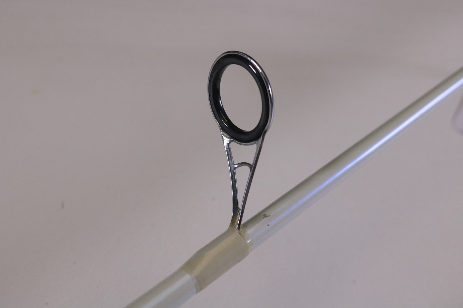 Close-up of the guide ring on a Duckett White Ice TR-DFWI68MHS 6'8" Medium Heavy Used Spinning Rod in good condition. Perfect for used gear enthusiasts or those considering our Rod and Reel Trade-In for store credit.