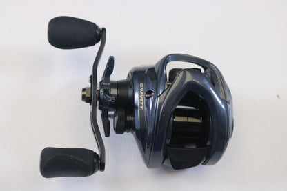A close-up photo of an Ark Fishing Gravity 3 G3107L 7.1:1 LH Used Casting Reel in excellent condition, dark blue with black handles—ideal for those seeking quality pre-owned gear or eyeing a rod and reel trade-in for store credit.