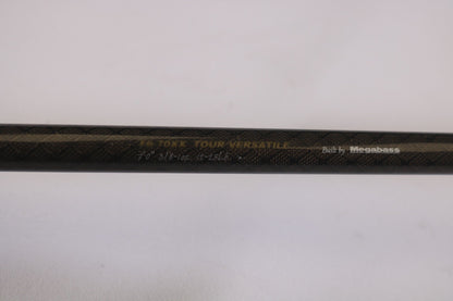A close-up of the Megabass Orochi XX F6-70XX Tour Versatile 7'0" Heavy rod with "Built by Megabass" etched on its textured dark surface. Ideal for our Rod and Reel Trade-In Program, offering store credit for well-maintained used gear.