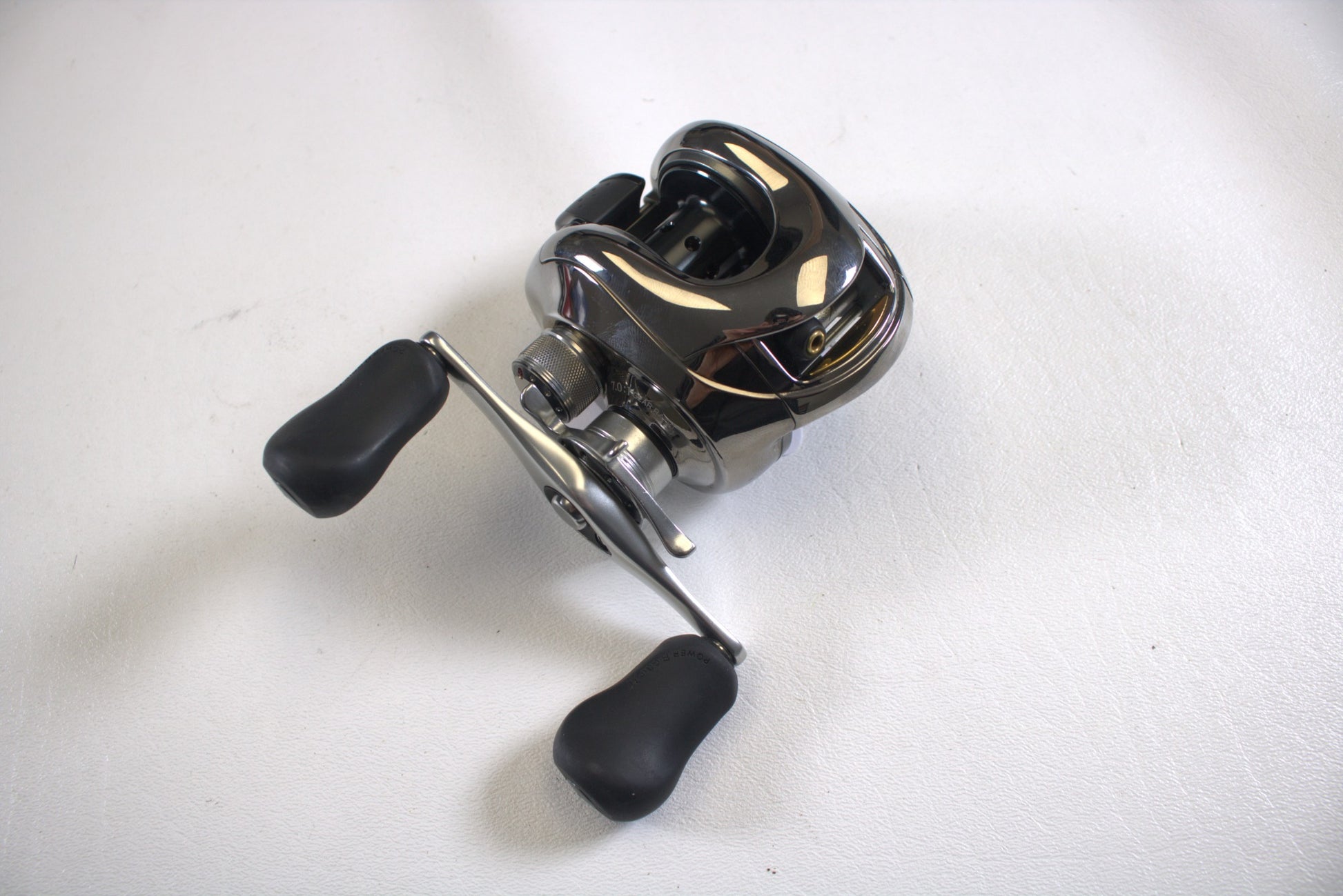 A close-up of a used Shimano Calais 200DC casting reel (7.0:1 gear ratio, black handles) in excellent condition, shown on a plain white surface.