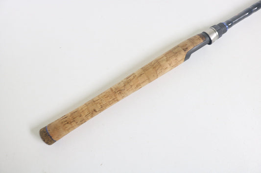 A close-up of the Dobyns Champion XP DC762SF Used Spinning Rod handle, featuring a cork grip and metal reel seat, from americanlegacyfishing, shown diagonally on a plain white background.