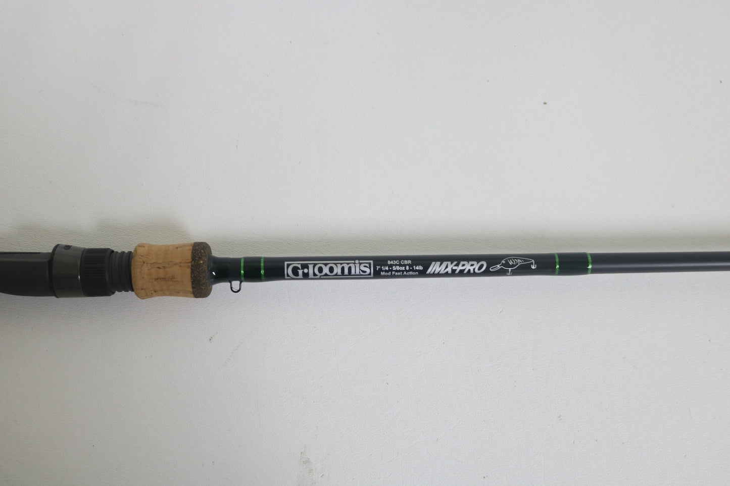 A G. Loomis IMX-Pro 843C CBR casting rod in excellent condition features a cork handle and black shaft with specifications in white text, set on a plain white background.