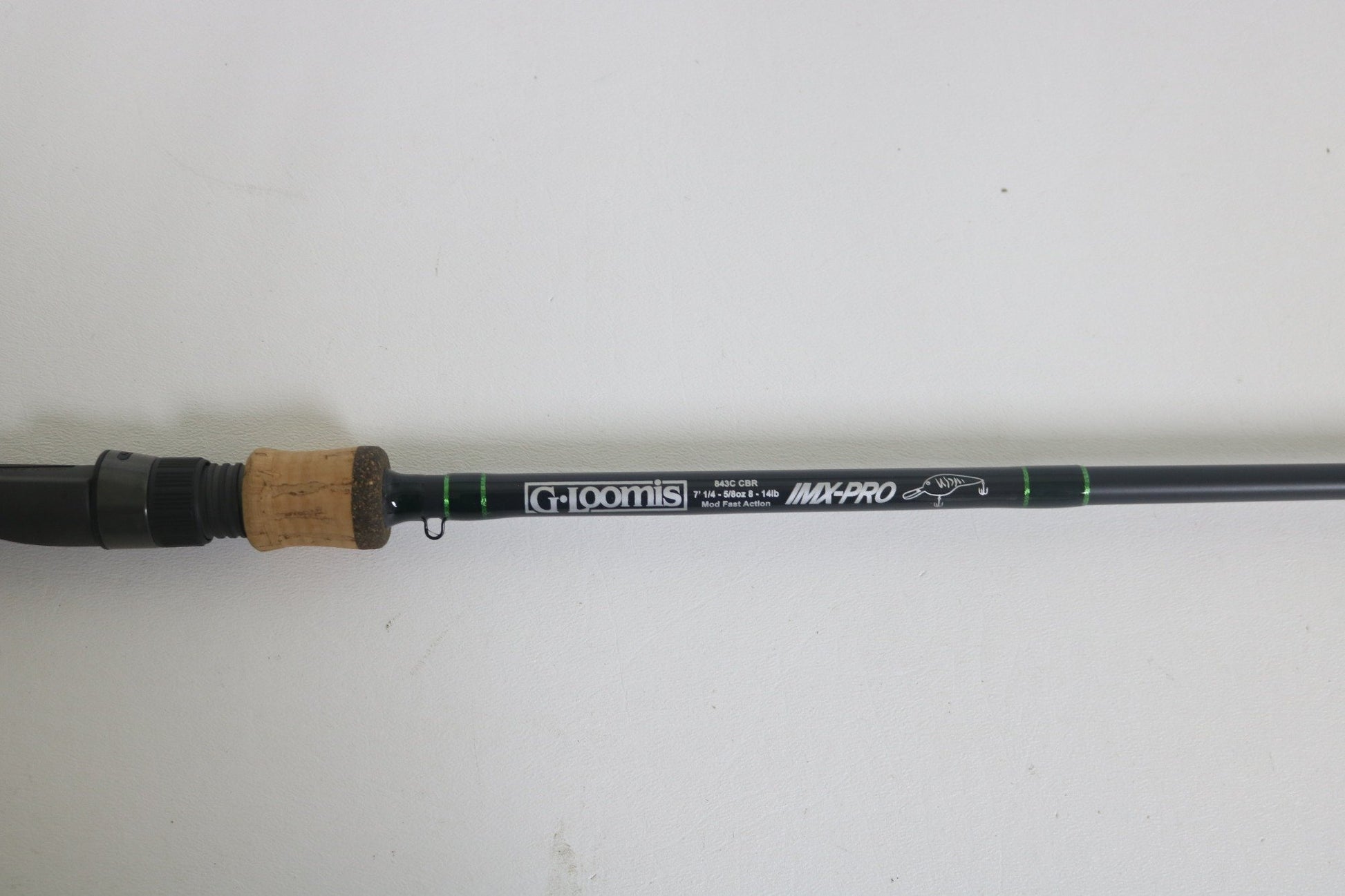 A G. Loomis IMX-Pro 843C CBR casting rod in excellent condition features a cork handle and black shaft with specifications in white text, set on a plain white background.