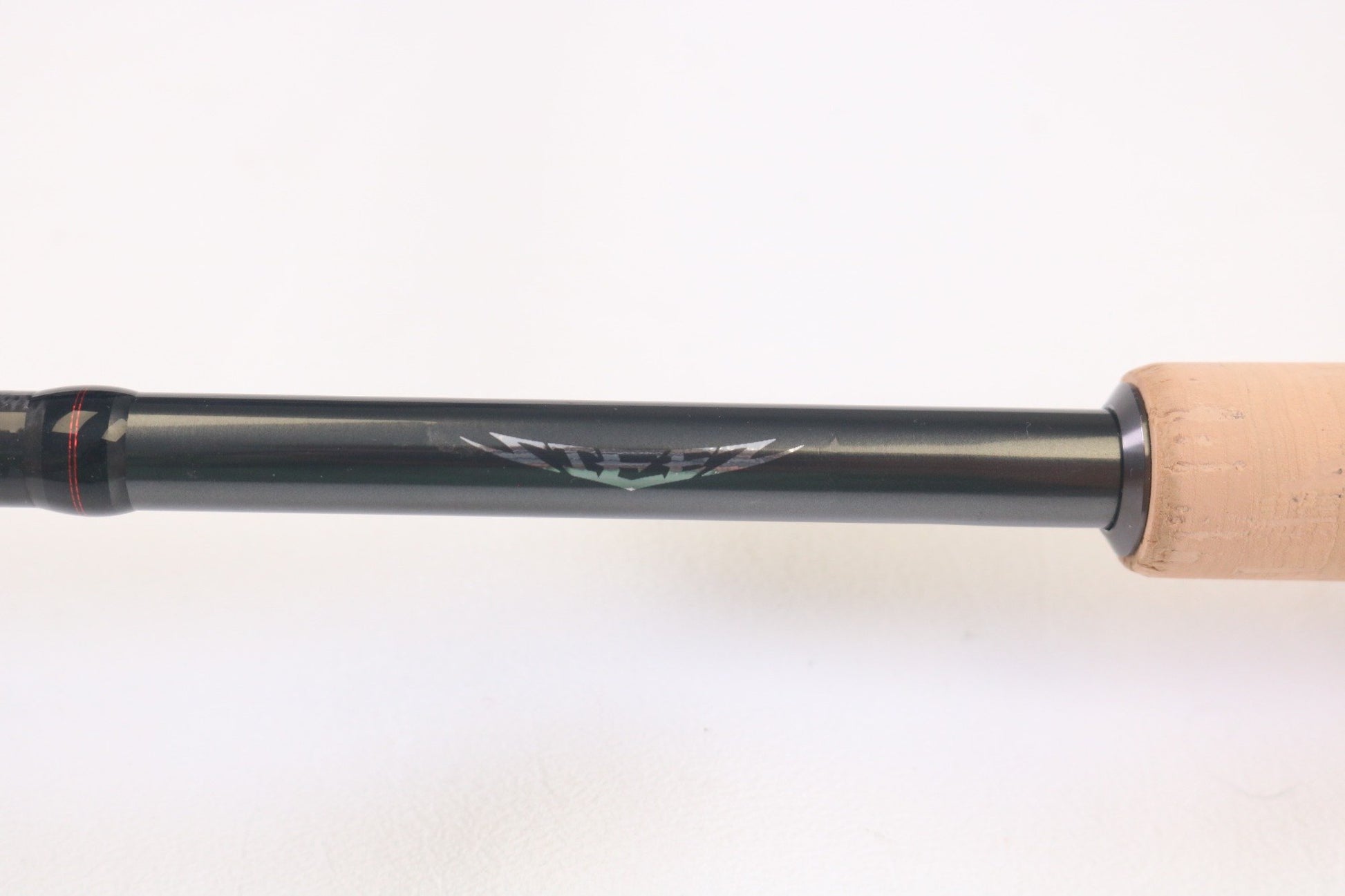 A close-up of the Daiwa Steez AGS STAGS761MMLFS 7'6" Medium Medium Light used spinning rod in mint condition, showcasing its black shaft with silver emblem and tan cork grip—perfect for anglers seeking quality pre-owned Daiwa gear.
