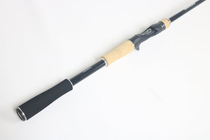 A Shimano Expride A EX172MHGA Used Casting Rod in excellent condition with a black finish and light wood and black handle, shown diagonally on a white background.