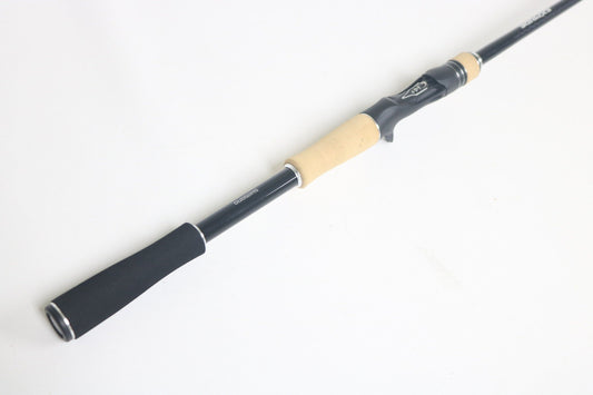 A Shimano Expride A EX172MHGA Used Casting Rod in excellent condition with a black finish and light wood and black handle, shown diagonally on a white background.