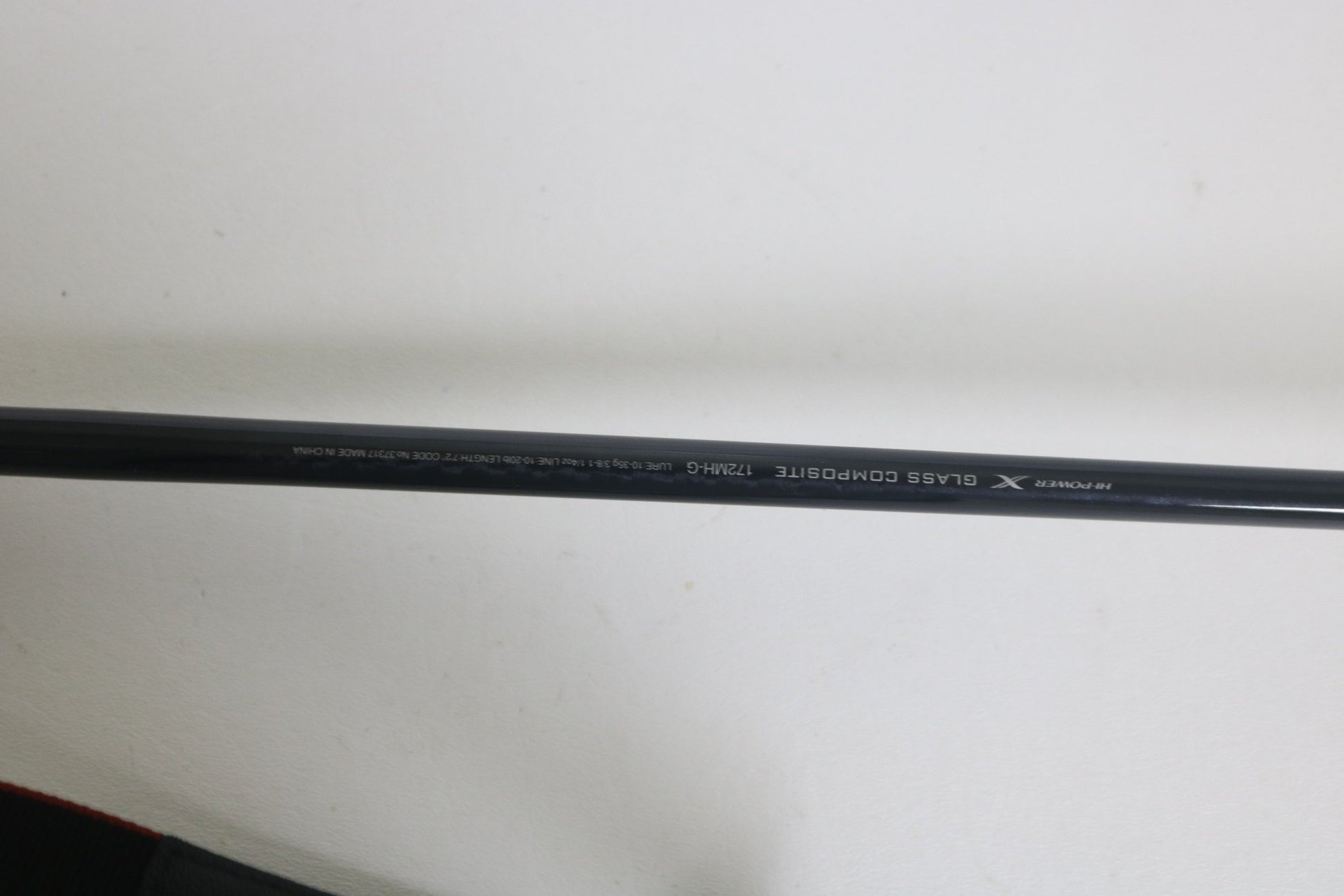 A close-up of a Shimano Expride A EX172MHGA used casting rod in excellent condition shows "GLASS COMPOSITE 7'2"MH" and "X" on its black surface, photographed against a plain white background.