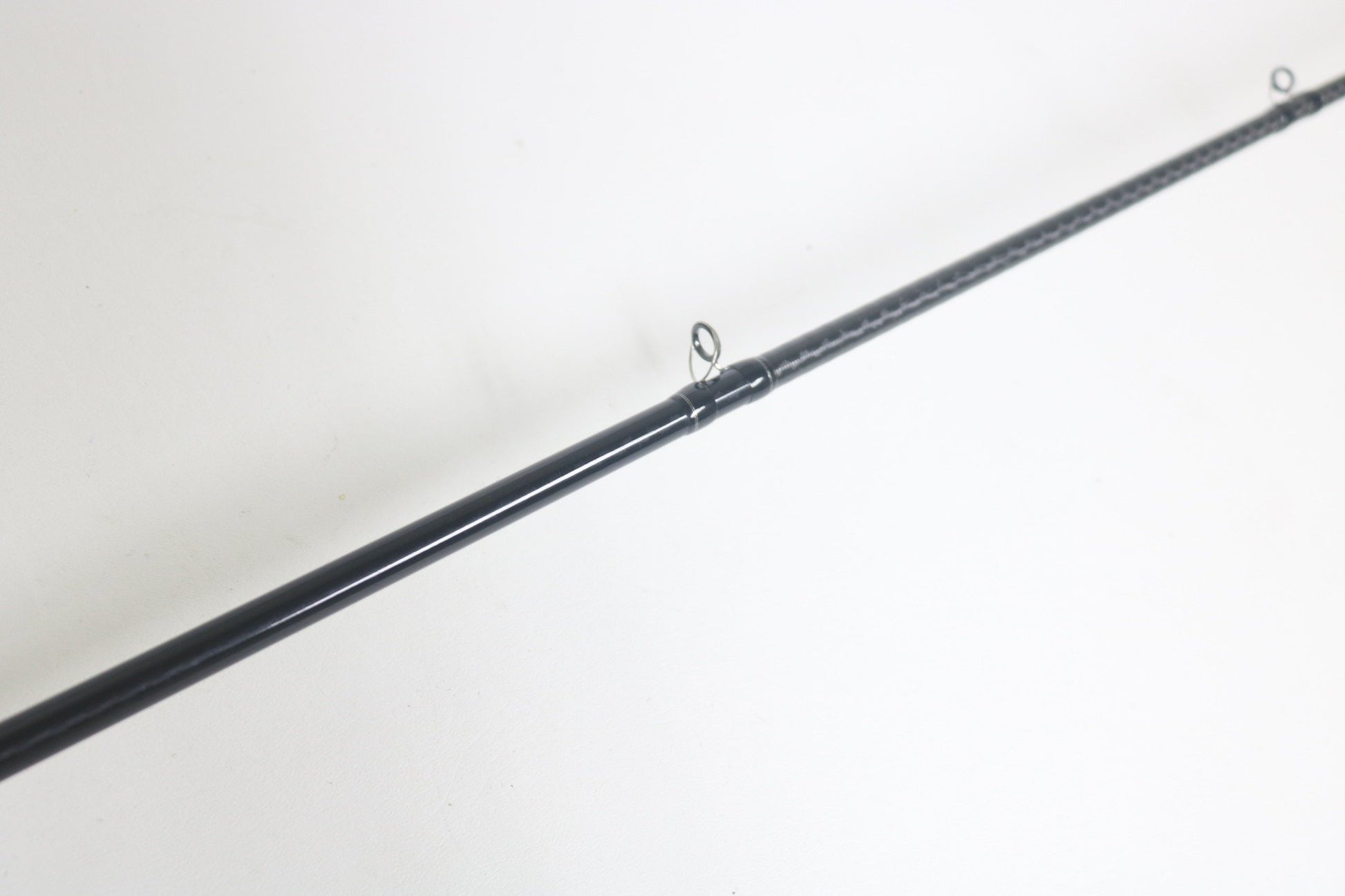 A close-up of a Shimano Expride A EX172MHGA Used Casting Rod in excellent condition, lying diagonally on a white surface, with two line guides visible.
