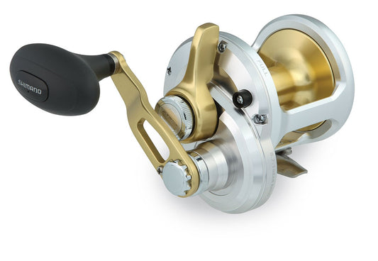 A close-up of the Shimano Talica TAC16 Lever Drag Reel by Shimano, featuring a gold and silver body, black handle grip, and precision-machined parts for smooth drag performance, displayed against a white background.