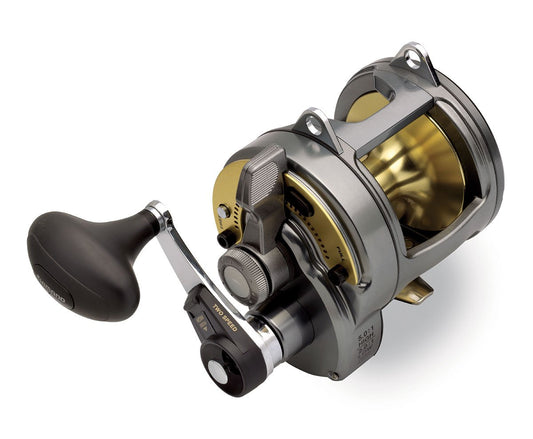 A close-up of the Shimano Tyrnos 20II 2-Speed Lever Drag Fishing Reel shows its metallic gold and silver finish, large ergonomic black handle, visible gears, and advanced lever drag system for modern fishing performance.